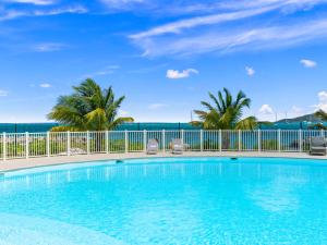 a swimming pool with palm trees and a fence at Ocean Breeze, Fully Renovated Beachfront 2 bdr in Baie Nettle