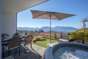 a hot tub with a table and chairs and an umbrella at Al Pianaccio by Lago Reisen in Trarego Viggiona
