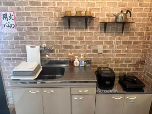 a kitchen with a sink and a brick wall at 掘っ立て小屋遊々 in Mine +10 photos