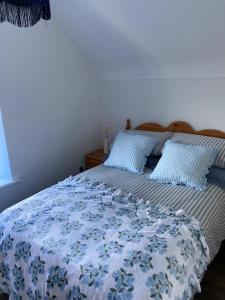 a bed with a blue and white blanket and pillows at The Cottage in Ramelton