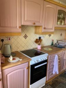 a kitchen with pink cabinets and a stove top oven at The Cottage in Ramelton