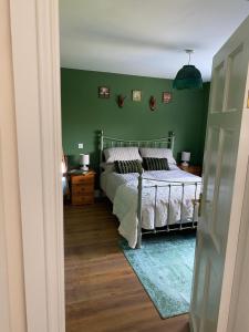 a bedroom with a bed and a green wall at The Cottage in Ramelton