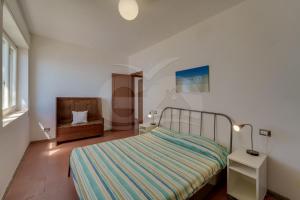 a small bedroom with a bed and a chair at Casa Bianca - Goelba in Pomonte