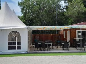 a white tent with tables and chairs in a yard at Camping Fontisson - Mobil home 3 pièces 4/5 personnes Climatisé MAE-1476 in Châteauneuf-de-Gadagne