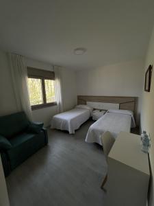 a hotel room with two beds and a couch at Habitaciones A Postiña in Areas