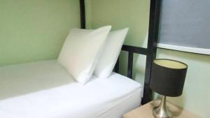 a bedroom with two beds with white pillows and a lamp at Chic Homestay Narathiwat in Ban Kam Pong Ba Ru