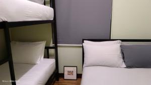 two bunk beds with white pillows and a picture at Chic Homestay Narathiwat in Ban Kam Pong Ba Ru
