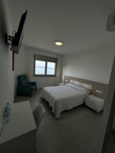a bedroom with a bed and a chair and a window at Habitaciones A Postiña in Areas