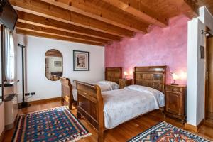 a bedroom with two beds and a pink wall at B&B Il Pettirosso in Negrar