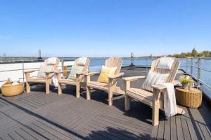 three chairs and a table on a deck with the water at Floatinghouse Sunday in Ribnitz-Damgarten +11 photos