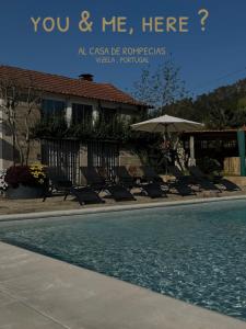 a pool with chairs and an umbrella in front of a building at Casa de Rompecias in Vizela