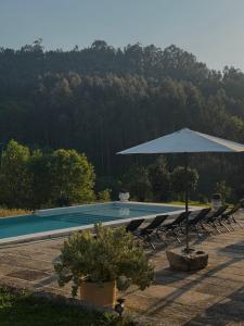 a swimming pool with an umbrella and chairs and a table at Casa de Rompecias in Vizela