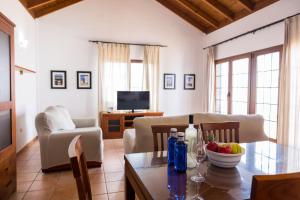 a living room with a table and a couch and a television at Villas & Apartamentos Tao Mazo in Lajares