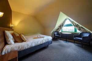 a bedroom with a bed and a window in a attic at Hotel Les Jardins De La Molignée in Dinant