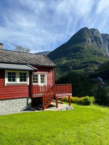 a bench in front of a red house with a mountain at Melkevoll Bretun Camping in Briksdalsbre