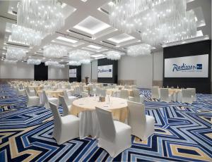 a conference room with tables and white chairs and chandeliers at Radisson Blu Hotel & Resort, Sohar in Sohar +113 photos