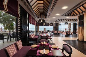 a restaurant with tables and chairs with a view of the ocean at Radisson Blu Hotel & Resort, Sohar in Sohar