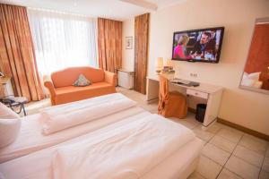 a hotel room with a bed and a tv on the wall at Gasthaus Gästekiste in Augsburg