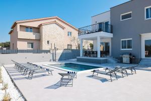 a patio with chairs and a pool and a building at Villa IviCasa with pool in Murvica