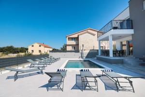 a patio with chairs and a pool and a building at Villa IviCasa with pool in Murvica