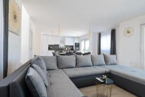 a living room with a gray couch and a kitchen at Villa IviCasa with pool in Murvica