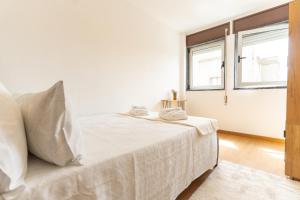 a bedroom with a bed with white sheets and a window at DouroParadise Apartment in Peso da Régua