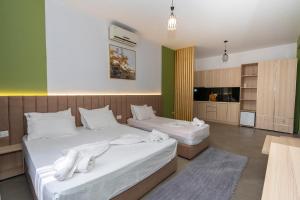 two beds in a room with green walls at Hotel Shkodra L in Shkodër