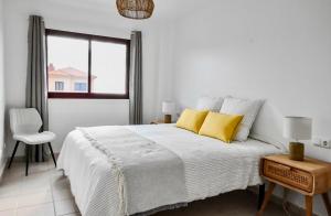 a white bedroom with a large bed with yellow pillows at La Casa del Toro in Corralejo
