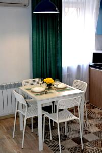une table à manger blanche avec des chaises et un rideau vert dans l'établissement Люкс с 2-мя спальнями в ЦЕНТРЕ, à Mykolaïv