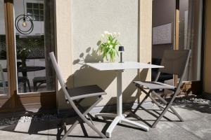 a white table with two chairs and a vase of flowers at AuxMoulins in Neuchâtel