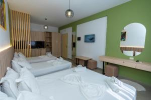a hotel room with three beds and a mirror at Hotel Shkodra L in Shkodër