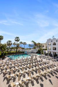 a group of lounge chairs and a pool at a resort at Mac Puerto Marina Benalmádena in Benalmádena