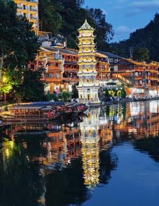 a reflection of a chinese building in the water at night at Phoenix Haven in Fenghuang County