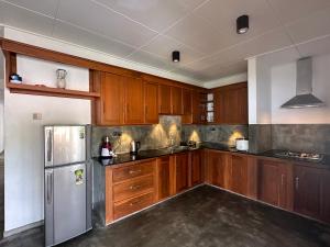 a kitchen with wooden cabinets and a stainless steel refrigerator at SAHAS Villa - Private Riverfront Garden Retreat in Beruwala in Beruwala