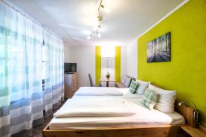 two beds in a room with a green wall at Hotelchen Schönblick in Gößweinstein
