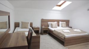 a bedroom with two beds and a desk and a table at Hotel Aldi in Rožaje