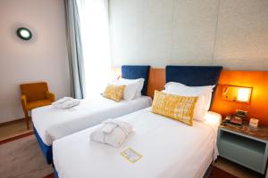 two beds in a hotel room with towels on them at voco Parma & Congressi by IHG in Parma
