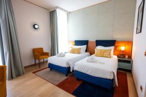 a hotel room with two beds and a chair at voco Parma & Congressi by IHG in Parma