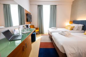 a hotel room with two beds and a laptop on a desk at voco Parma & Congressi by IHG in Parma