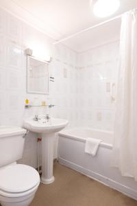 a white bathroom with a toilet and a sink at The Caledonian Tower Hotel in Blackpool
