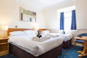 two beds in a hotel room with blue carpet at The Caledonian Tower Hotel in Blackpool