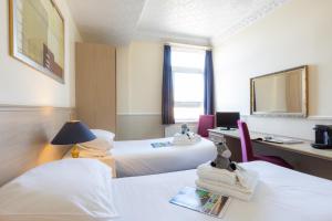 a hotel room with two beds and a desk at The Caledonian Tower Hotel in Blackpool +13 photos