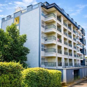 a tall white building with bushes in front of it at Amani Place in Ruaka