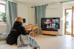 a woman sitting on a bed playing a video game at Casa Galya with private patio by GardaDoma in Brenzone sul Garda