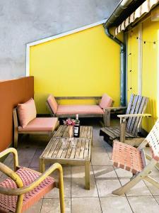 a patio with chairs and tables and a yellow wall at Le spacieux - centre ville in Gap