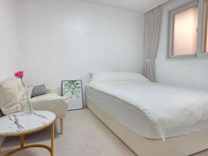 a white bedroom with a bed and a chair at 메종 블랑 서울 in Seoul