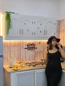 a woman standing in a kitchen talking on a cell phone at Maya House - Villa Cap Zbib in Banī ‘Aţāʼ