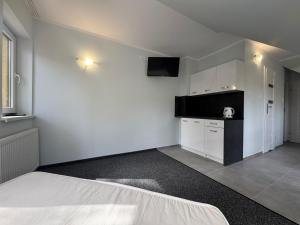 a white room with a bed and a kitchen at Willa Paweł in Pogorzelica