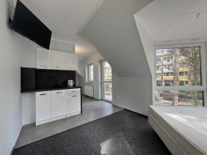 an attic kitchen with white cabinets and a large window at Willa Paweł in Pogorzelica