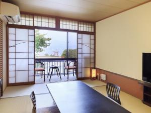 a room with a table and chairs and a balcony at Kikunoya in Miyajima